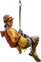 Smiling man in a yellow shirt and orange helmet ziplines while making a shaka hand gesture.