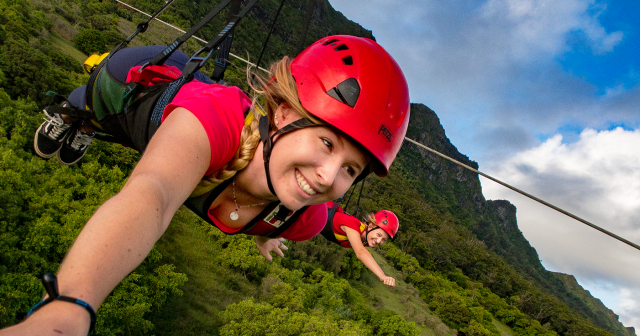 Outfitters Kauai guides smiling outdoors on Kīpū Ranch with green hills behind them.