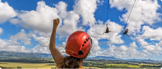 Zipliner soaring over green Kauai forest canopy during a guided tour.