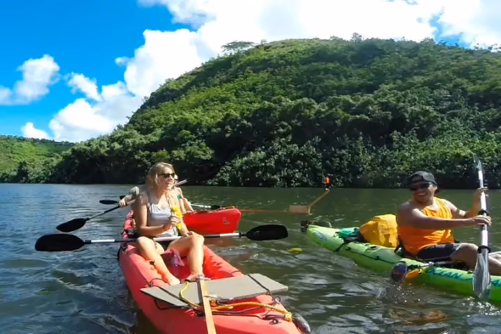 Guests kayaking on a calm Kauai river surrounded by tropical greenery.