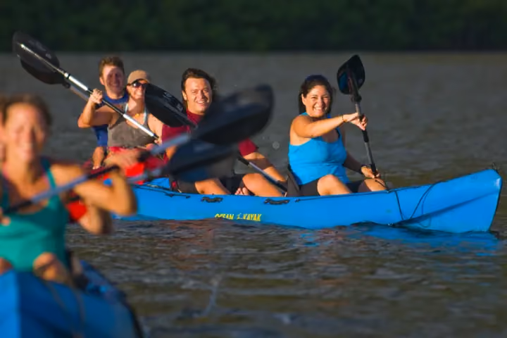Guests kayaking on a calm Kauai river surrounded by tropical greenery.