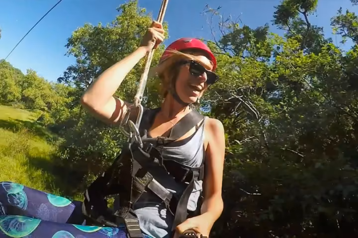Guest ziplining over lush green Kauai forest and valleys.