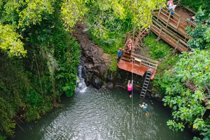 Guest splash-landing from a water zipline into a forest swimming hole.