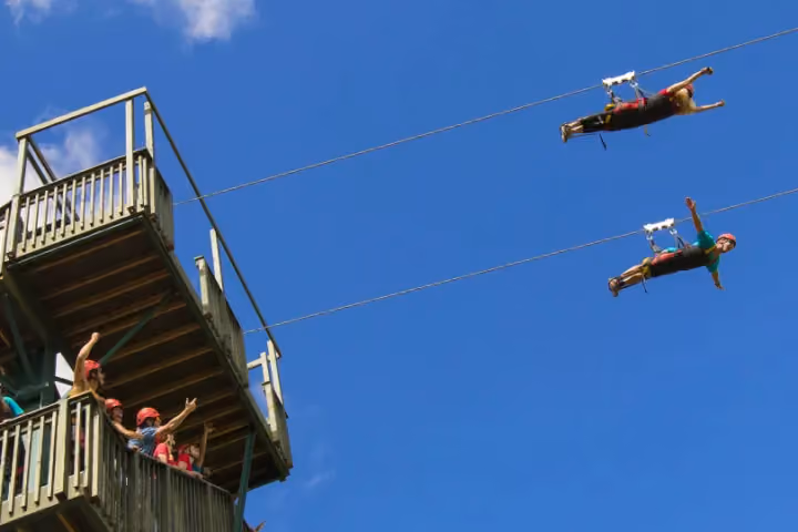Guest ziplining over lush green Kauai forest and valleys.