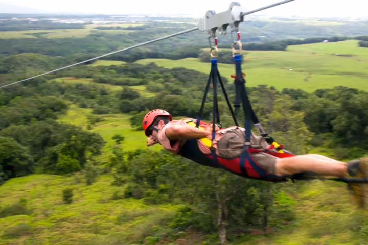 Guest ziplining over lush green Kauai forest and valleys.