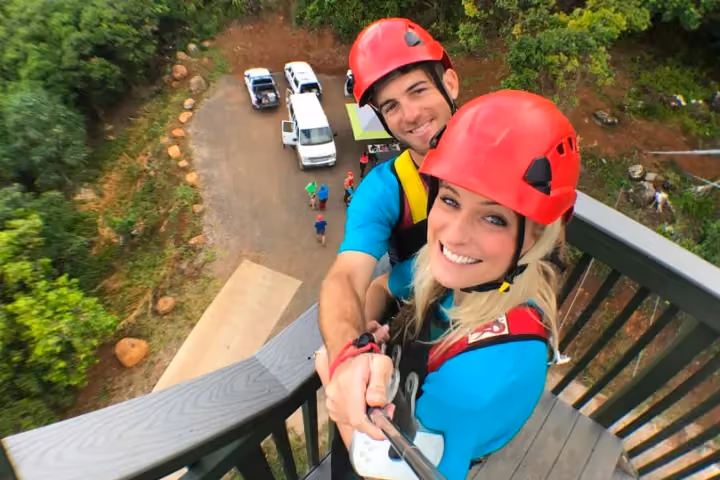 Guest ziplining over lush green Kauai forest and valleys.