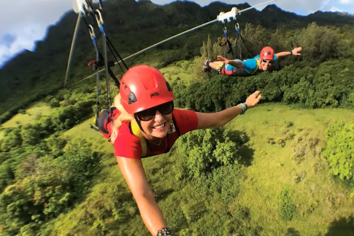 Guest ziplining over lush green Kauai forest and valleys.