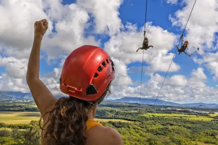 Guest ziplining over lush green Kauai forest and valleys.