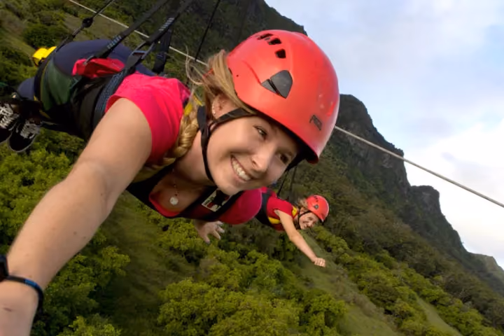 Guest ziplining over lush green Kauai forest and valleys.