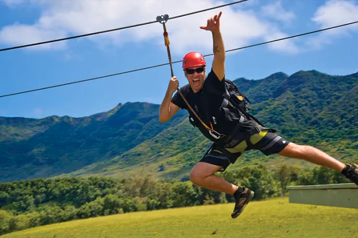 Zipliner soaring over green Kauai valleys on a scenic tour.