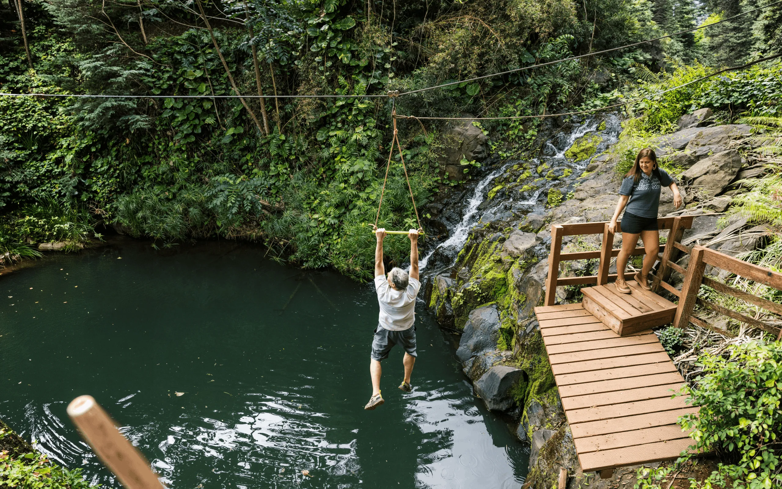 Guest ziplining over lush green Kauai forest and valleys.