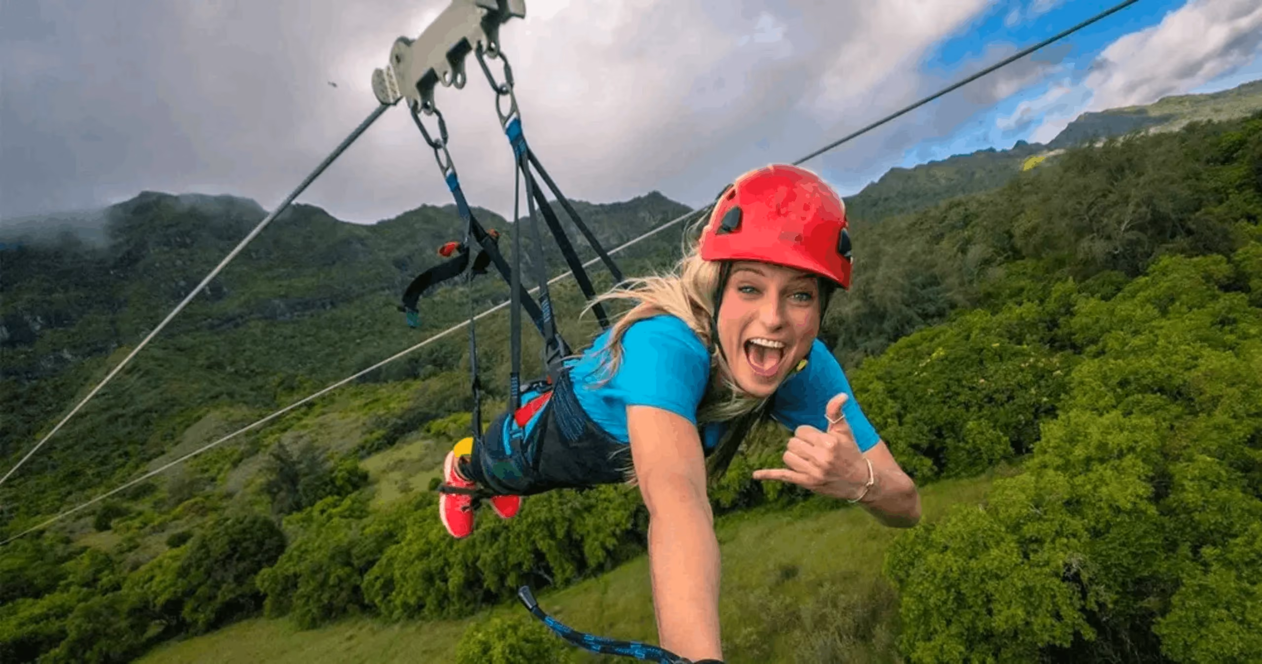Guest ziplining over lush green Kauai forest and valleys.
