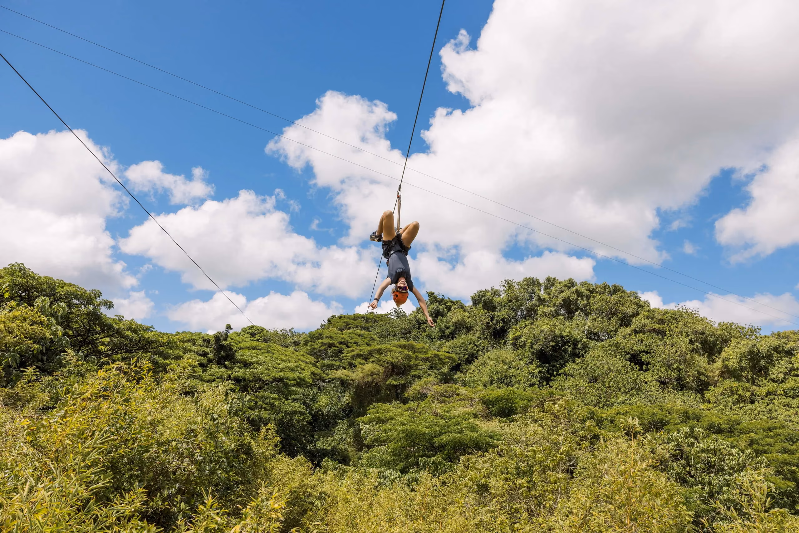 Guests on an AdrenaLine zipline course over lush Kauai forest.