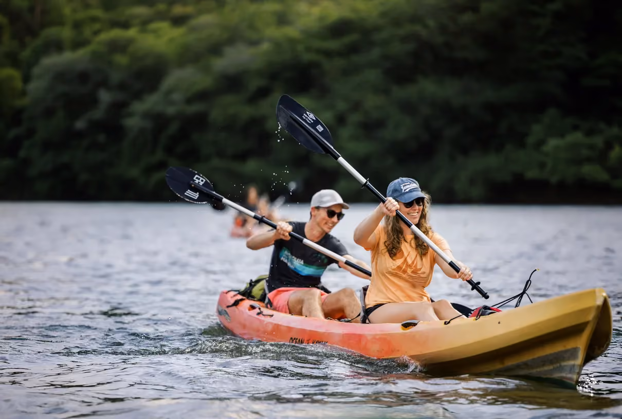 Guests kayaking on a calm Kauai river surrounded by tropical greenery.