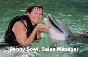 Peggy Sowl, Sales Manager at Outfitters Kauai, smiling in the water with a dolphin