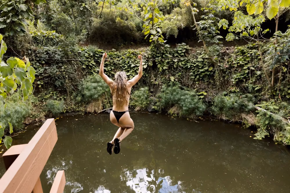 Guest riding the Water Zipline into Bamboo Pool at Outfitters Kauai on Kauaʻi