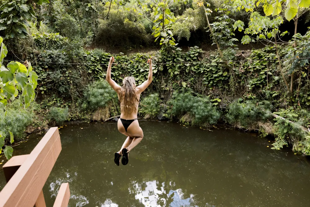 Guest dropping from the water zipline into Bamboo Pool at Kīpū Ranch