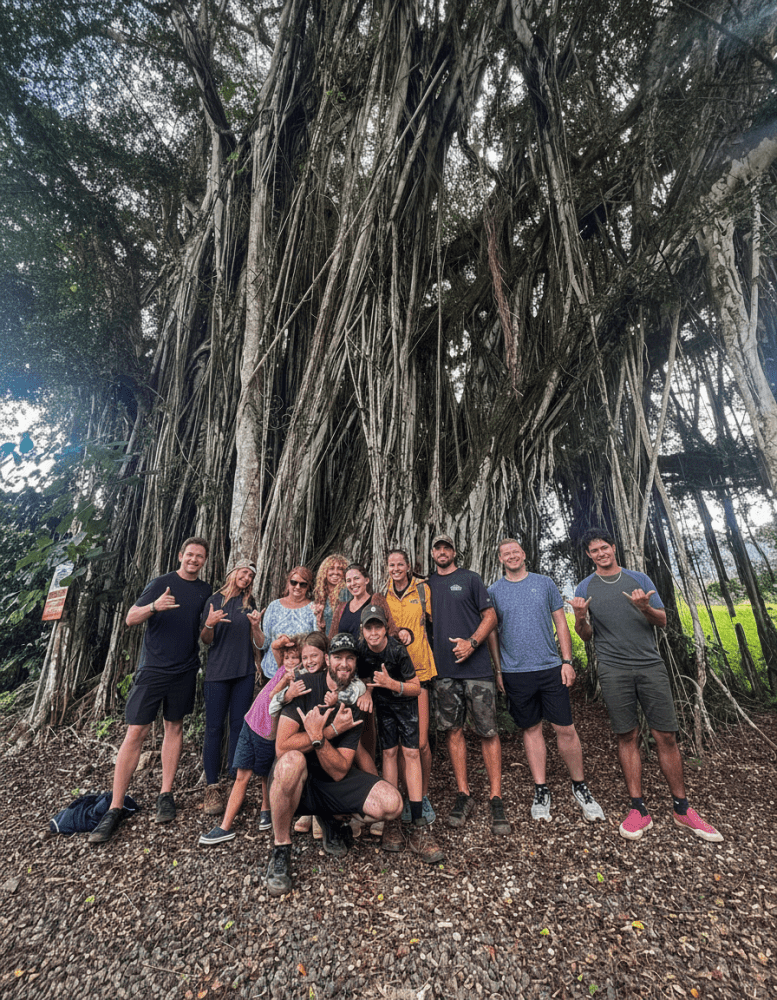 Group posing in front of a giant banyan tree at Kīpū Ranch after their zipline tour