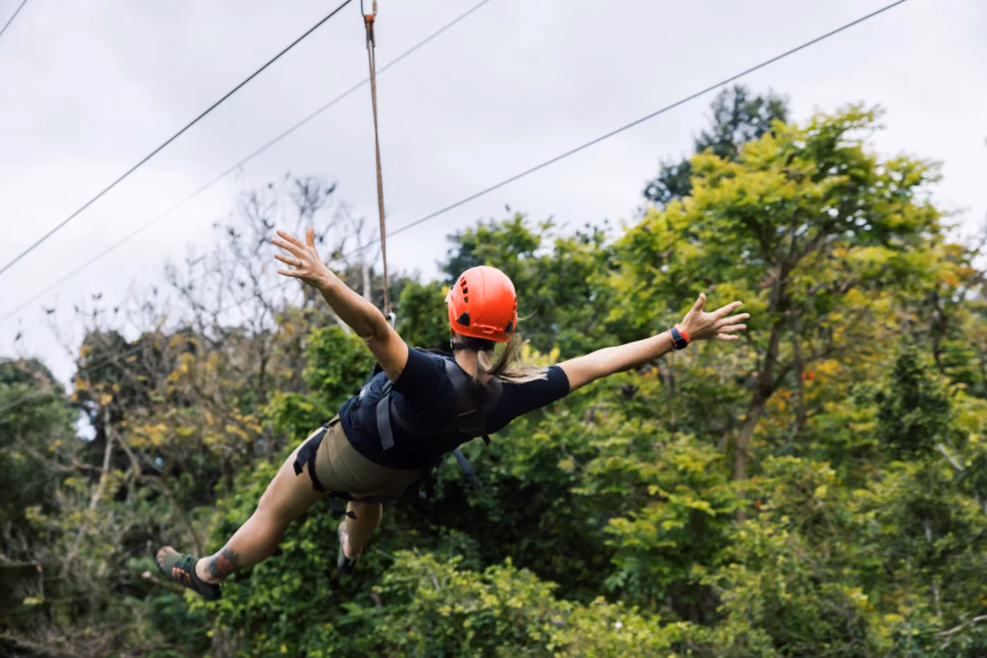 Person zip-lining through tropical forest canopy on Kauai adventure tour experience