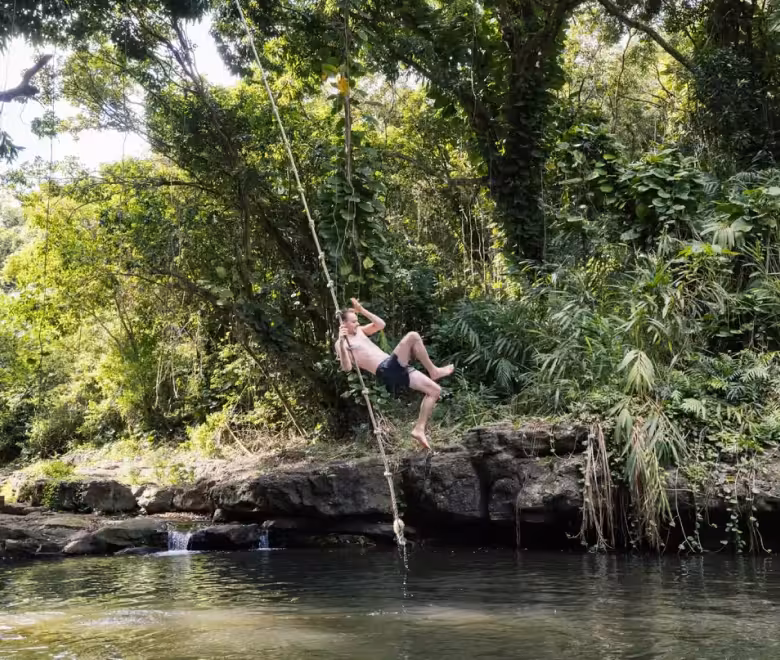 Guest swinging on the Pirate Pool rope swing on the Hidden Valley Falls kayak and hike tour