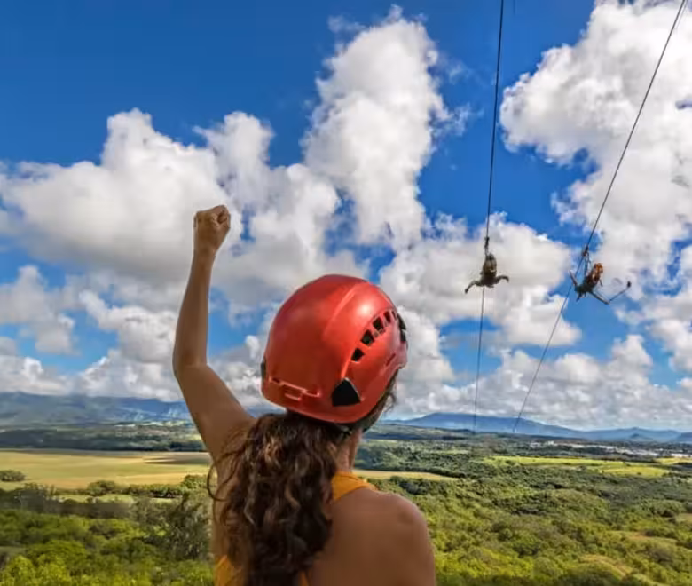 Guest cheering from the FlyLine tower as two zipliners race side by side over Kīpū Ranch