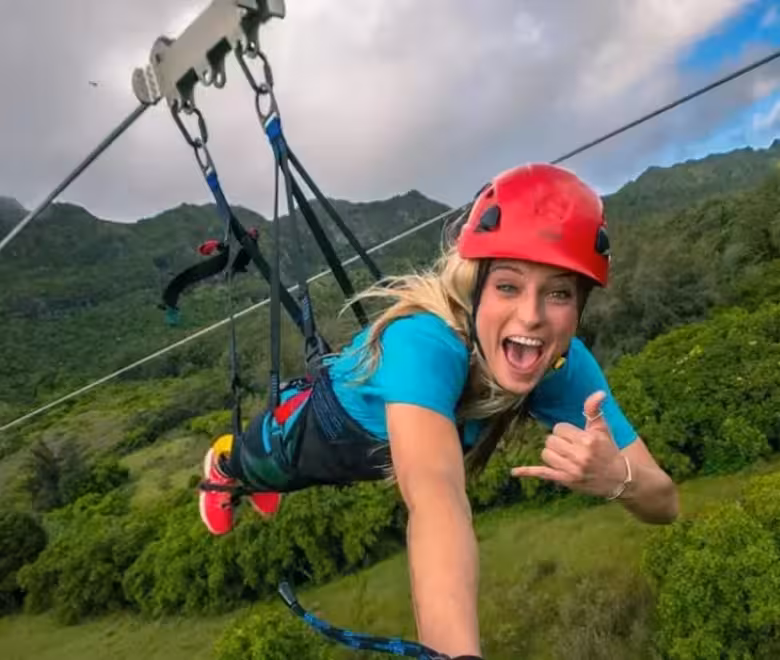 Zipliner throwing a shaka while flying headfirst on the FlyLine finale of the Nui Kauaʻi zipline tour