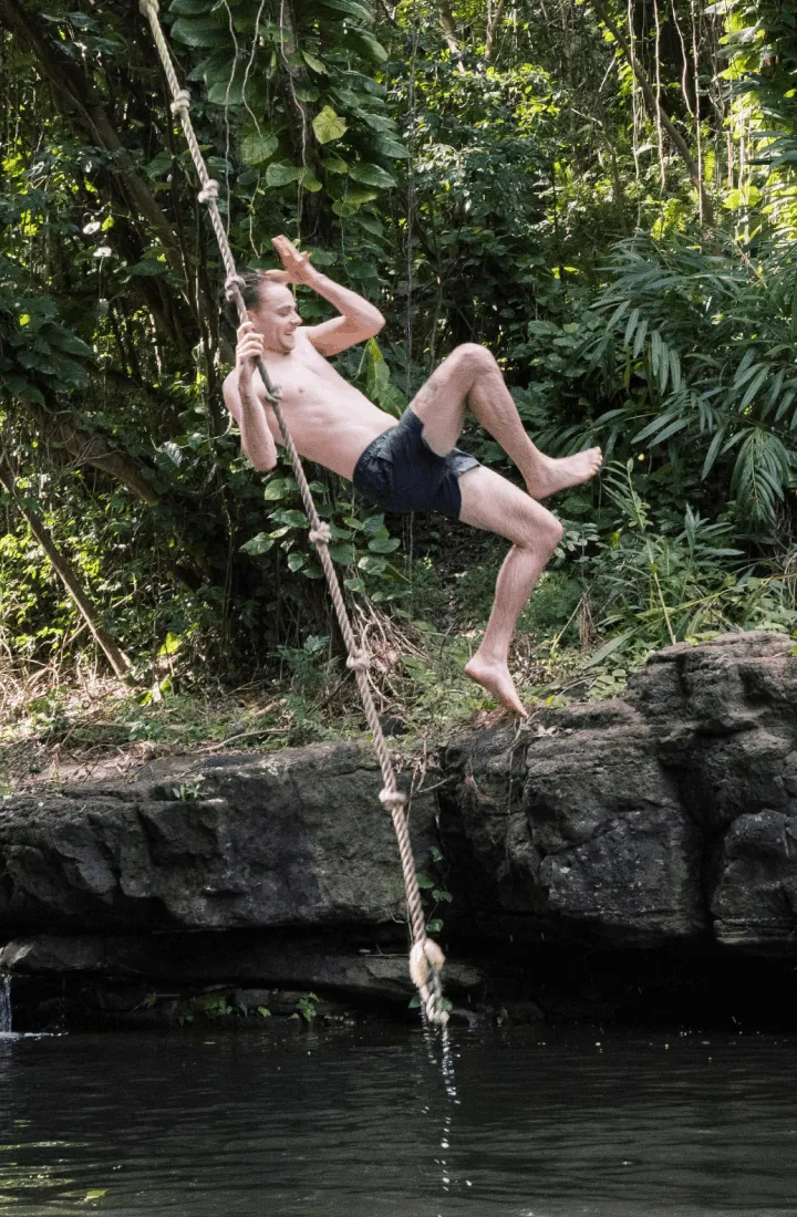 Guest on the Pirate Pool rope swing at Kīpū Ranch on Kauaʻi