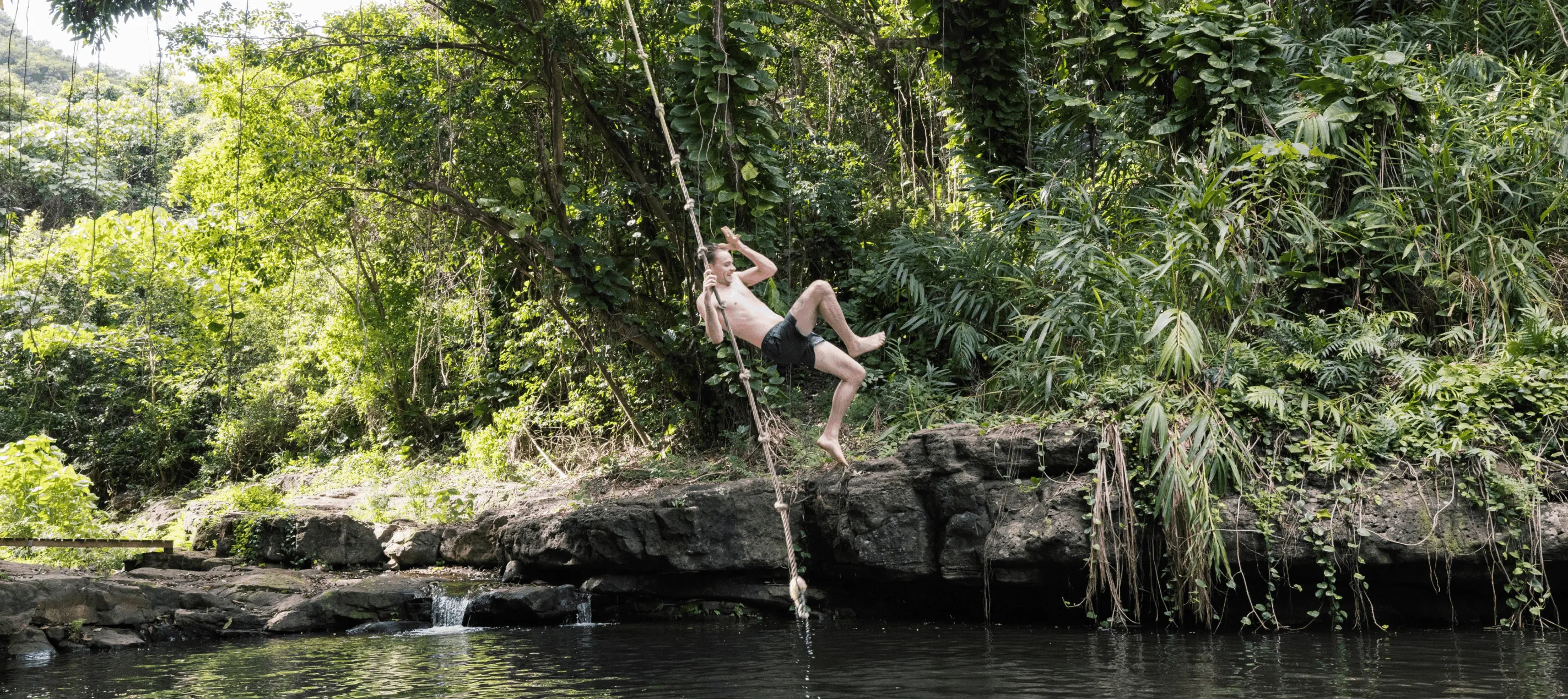 Guest swinging on the Pirate Pool rope swing at Kīpū Ranch, a Pirates of the Caribbean filming location