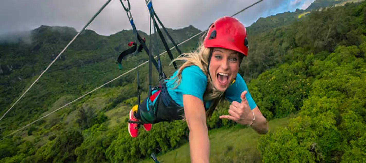Zipliner throwing a shaka while flying headfirst on the FlyLine, Hawaiʻi's longest zipline