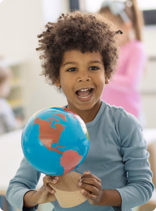 A boy smiling with plastic globe on hand