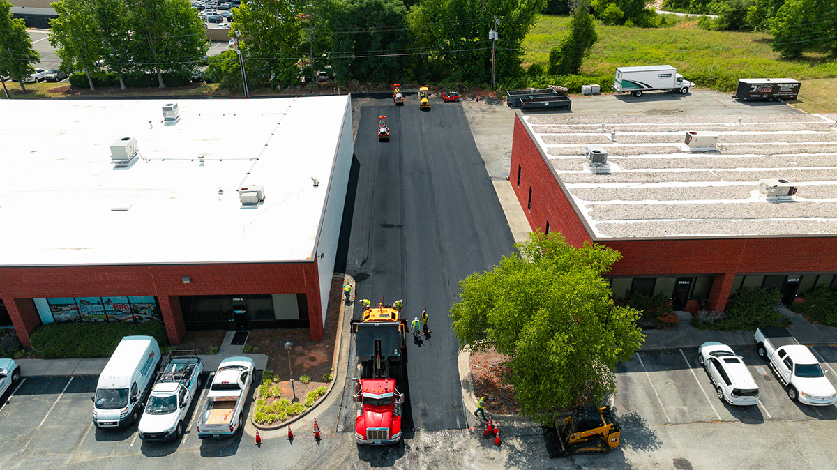 Aerial view of paving crew laying new asphalt in loading lane between buildings at Wendover Business Park, Greensboro NC