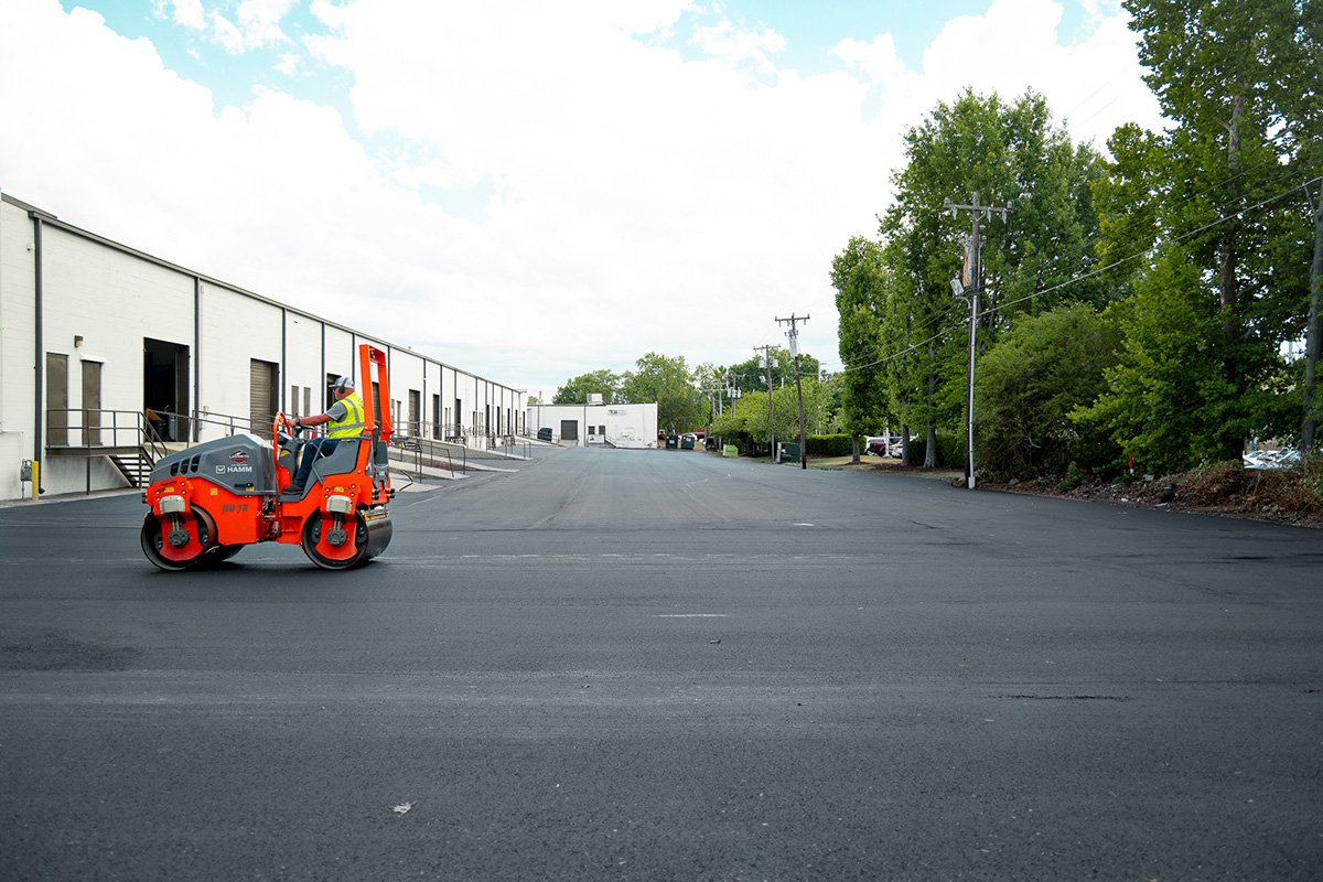 Asphalt roller compacting freshly paved driveway between buildings at Wendover Business Park, Greensboro NC