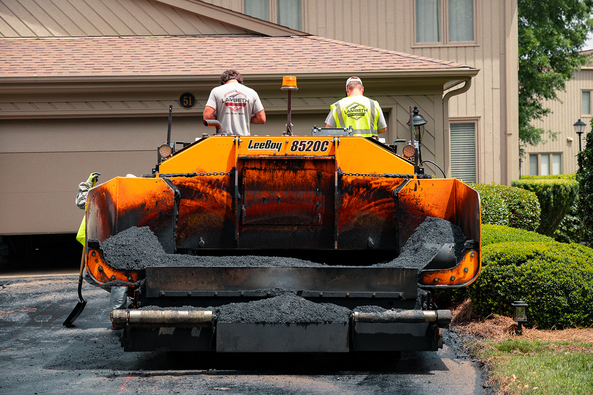 Lambeth Asphalt Services crew operating a LeeBoy 8520C paver during residential driveway paving at the Friendly West property in Greensboro, NC.