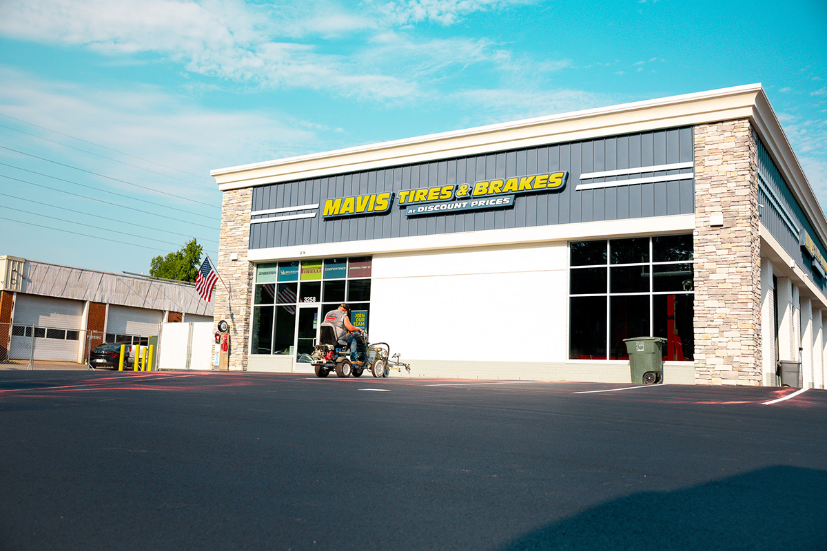 Lambeth Asphalt Services crew striping parking lot in front of new Mavis Tire & Brakes storefront, Greensboro NC