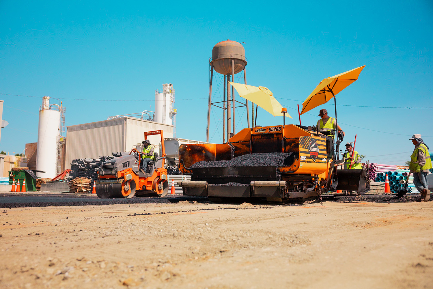 Lambeth Asphalt Services crew operating a SealMaster ride-on sealcoating machine at a warehouse dock, Durham NC