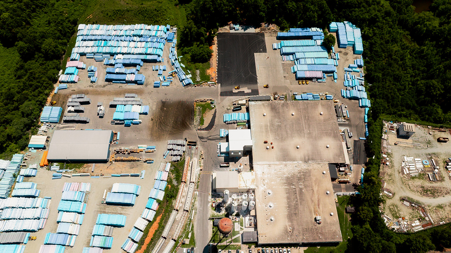 Aerial overview of the National Pipe and Plastics facility in Colfax, NC showing extensive PVC pipe storage yards and a freshly paved staging area