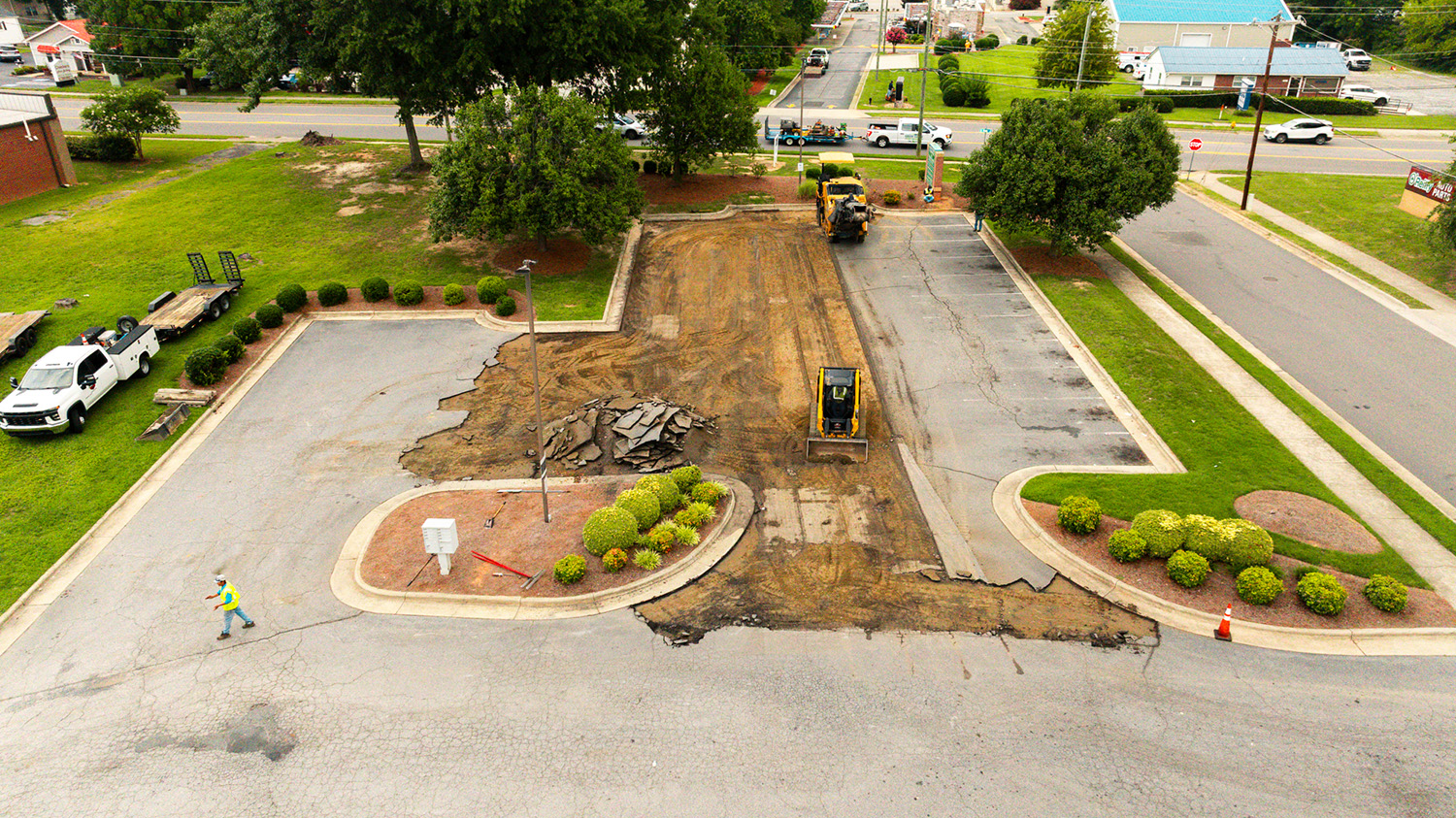 Aerial view of skid steer clearing milled asphalt from a landscaped entrance drive at Park Center Management, Kernersville, NC