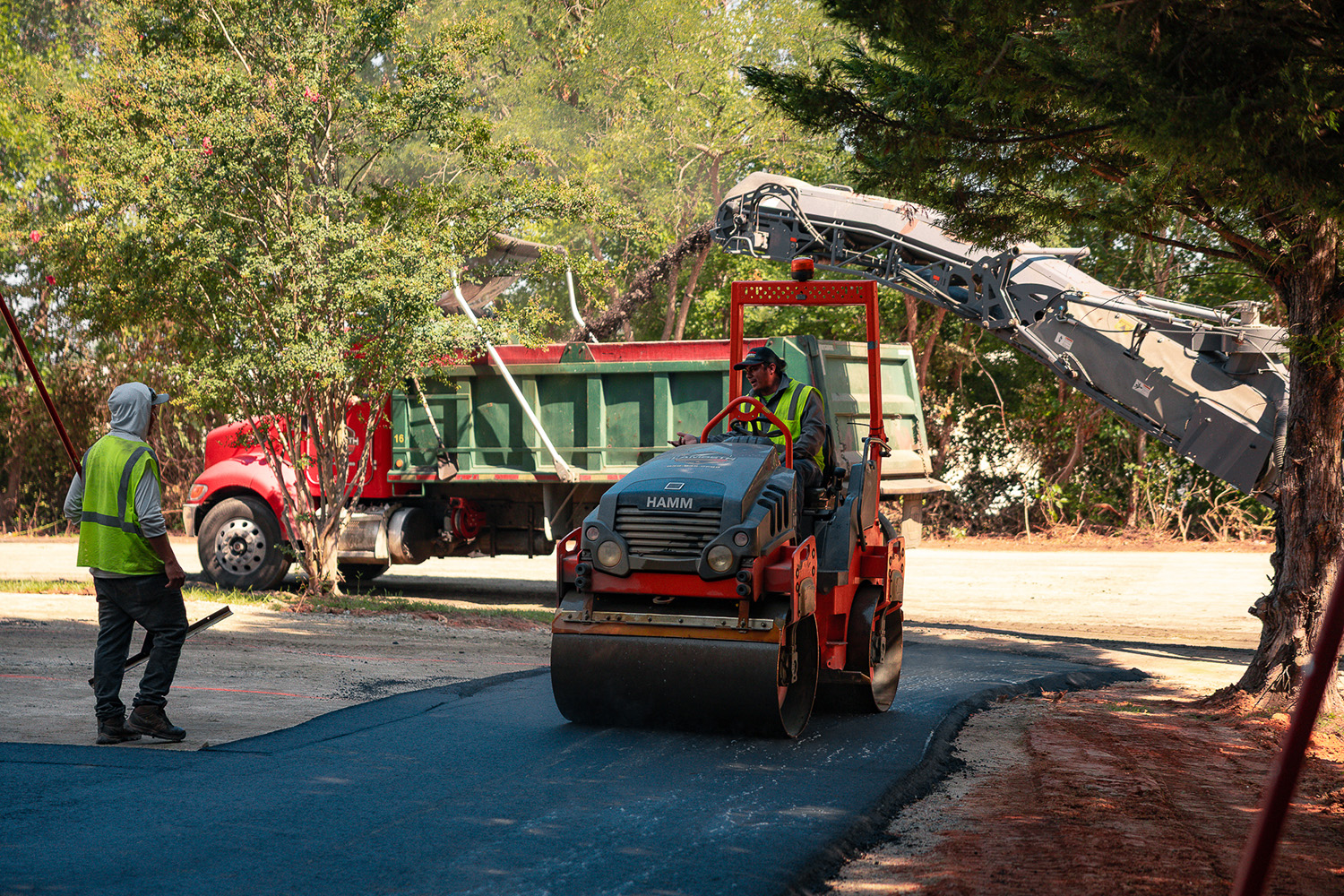 Lambeth Asphalt Services crew operating a HAMM roller as a dump truck delivers asphalt at Gexpro Services, High Point, NC