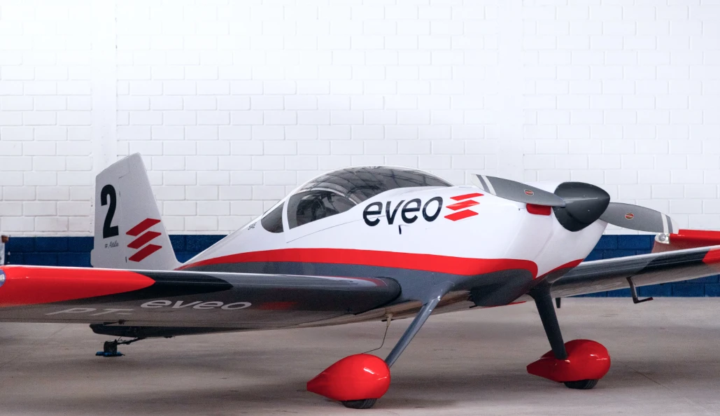 Aviao de pequeno porte com a marca EVEO na fuselagem, parado em um hangar