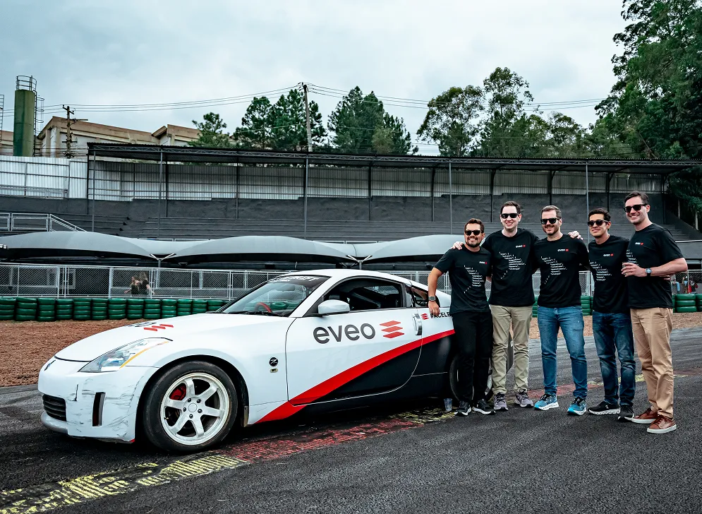Profissionais da EVEO ao lado do carro de corrida com a marca EVEO, em autodromo