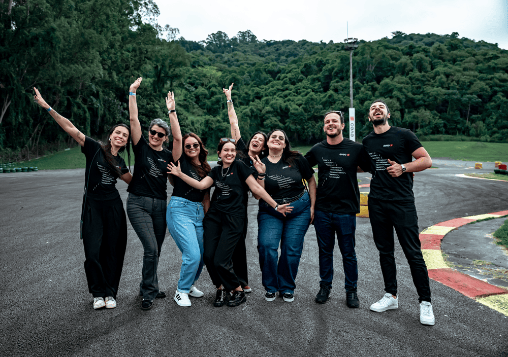 Equipe da EVEO de camiseta preta com a marca, sorrindo durante um evento ao ar livre