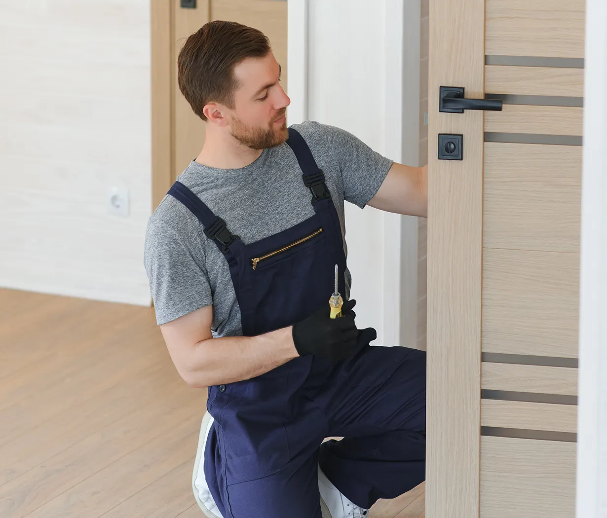 Locksmith fixing wooden door lock indoors.