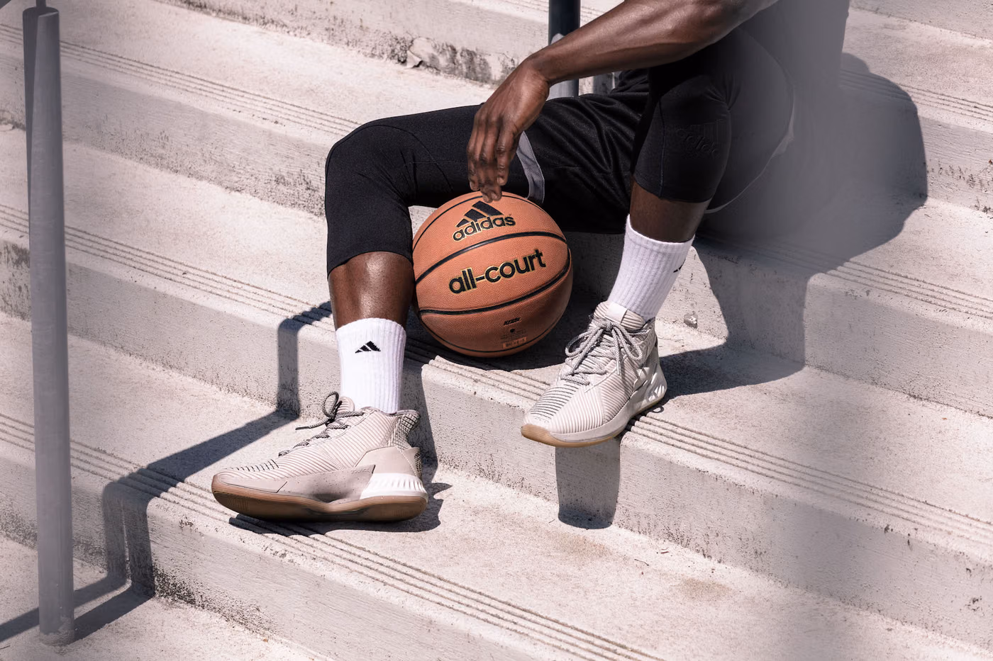 On-model photography of the adidas D Rose 9 shoes on outdoor court steps, shot in Portland