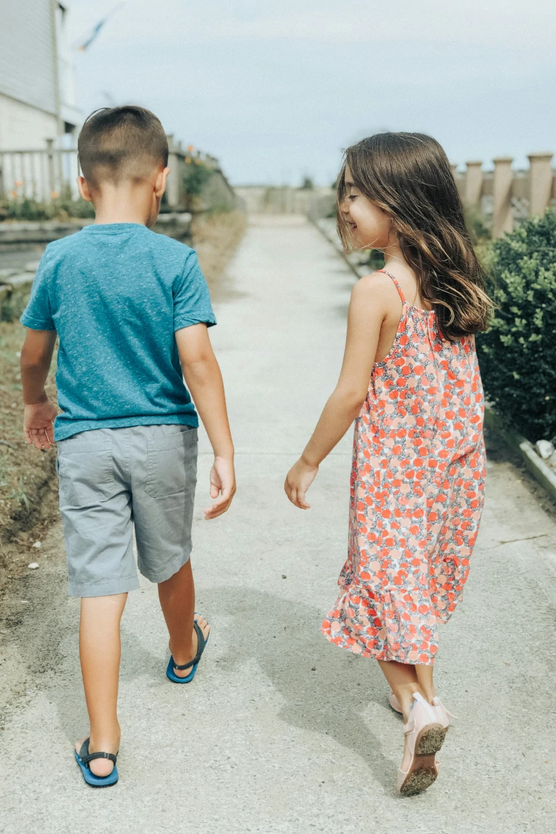 a girl and boy walking away holding hands
