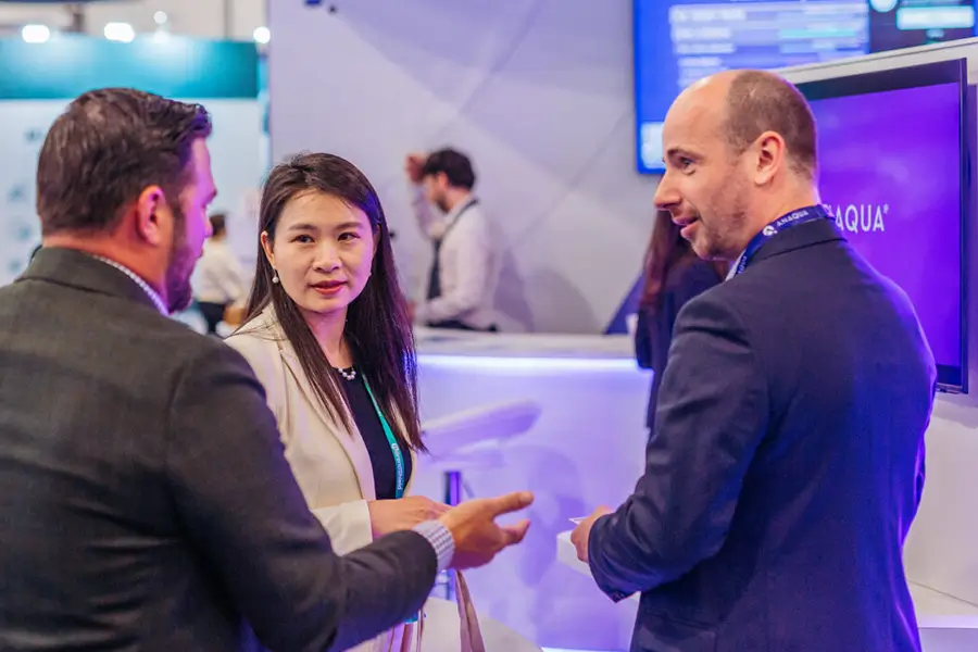 Anaqua exhibition stand with illuminated overhead branding, demonstration towers and hospitality areas