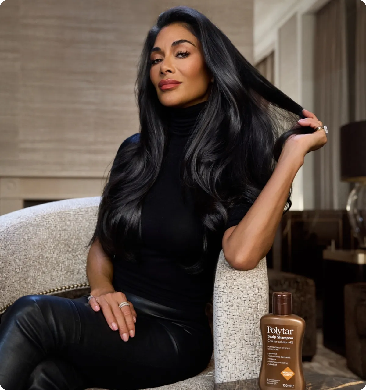 Woman with long black hair in black outfit sitting on chair holding her hair, Polytar shampoo bottle nearby.