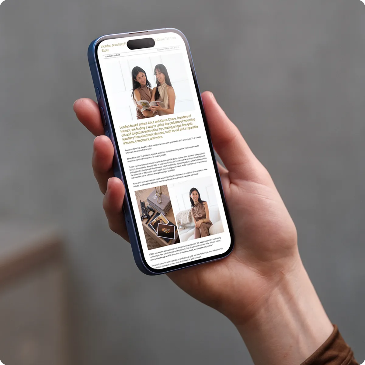 Hand holding a smartphone showing an article about London-based sisters creating gold jewelry from electronic waste.