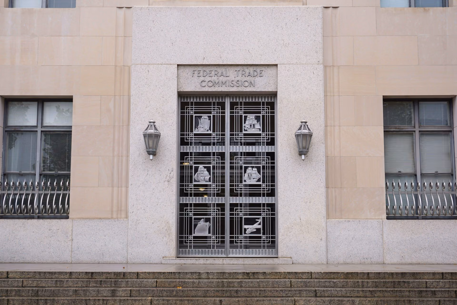 Entrance of the Federal Trade Commission building with metal doors featuring ship and airplane designs.