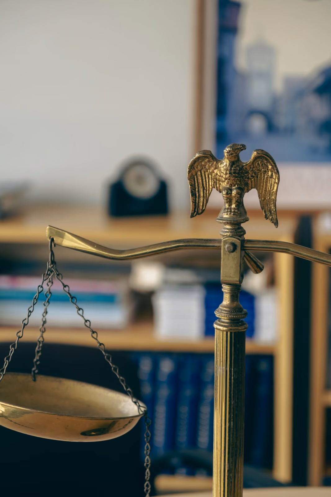 Close-up of a brass scales of justice with an eagle ornament in a law office setting.