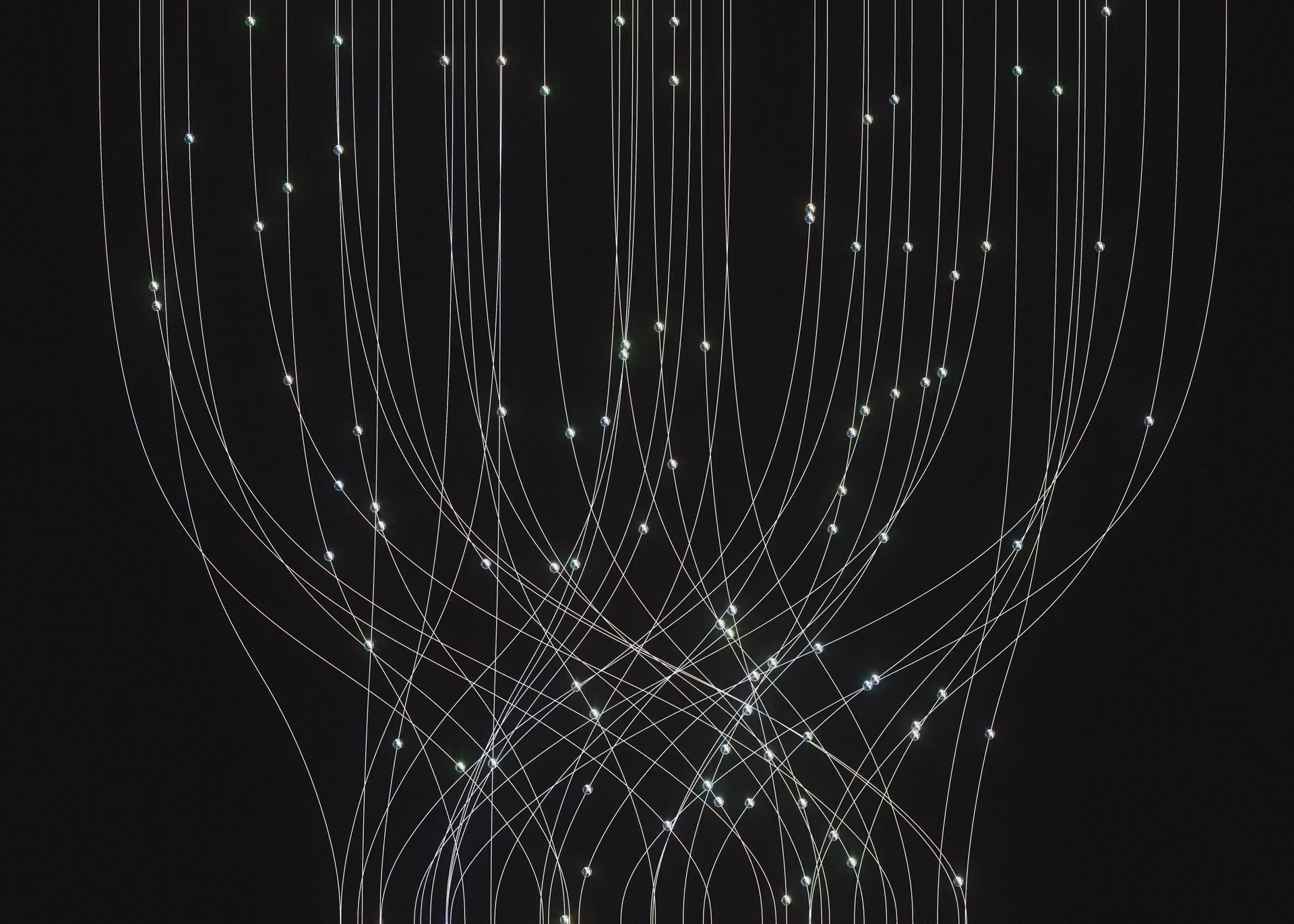 Curved thin white lines with glowing white dots on a black background resembling abstract light trails.